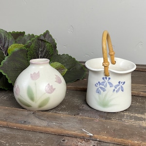 May include: A white ceramic mug with a black handle and the text "But First, Coffee" in a handwritten style. The mug is on a white surface. The mug is likely 325 ml.