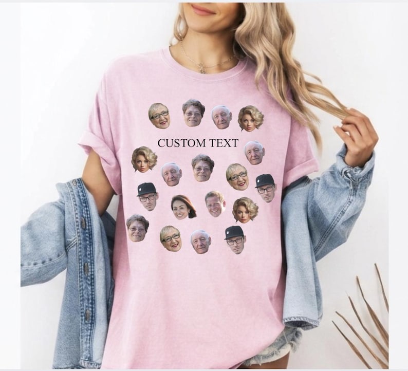 May include: A light pink t-shirt featuring a collection of faces arranged in a pattern. The shirt has the words "CUSTOM TEXT" printed on it. The shirt is a casual style.