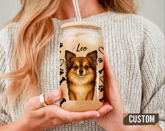 May include: A clear glass tumbler with a wooden lid and a straw. The tumbler features a custom design of a brown and tan Chihuahua with the name "Leo" above it. Black paw prints, bones, and hearts decorate the glass.