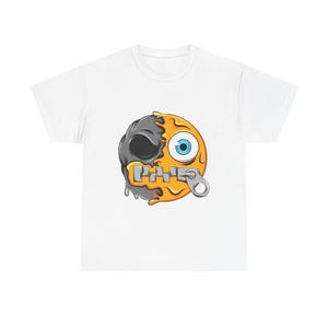 Könnte beinhalten: Ein weißes T-Shirt mit kurzen Ärmeln und einem zentralen Grafikdruck eines kreisförmigen Gesichts, das in zwei Hälften geteilt ist. Eine Seite ist ein dunkelgrauer Totenkopf, die andere ein leuchtend gelbes, schmelzendes Gesicht mit blauem Auge.