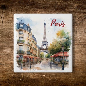 Puede incluir: Azulejo de cerámica cuadrado con una pintura de acuarela de una escena callejera parisina, con la Torre Eiffel y la palabra "París" en escritura roja. La imagen incluye edificios, árboles y toldos de café.
