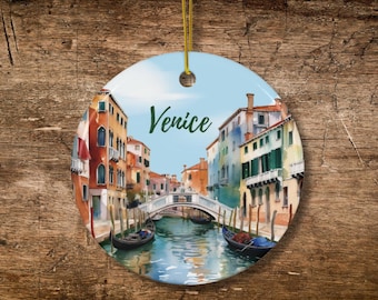 May include: Round ceramic ornament featuring a watercolor painting of Venice, Italy. The image shows colorful buildings, canals, gondolas, and a bridge. The word "Venice" is written in green script across the sky.