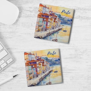 May include: Two square coasters with a watercolor painting of Porto, Portugal. The image features colorful buildings along a river, boats, and a bridge. The word "Porto" is written in blue script on each coaster.