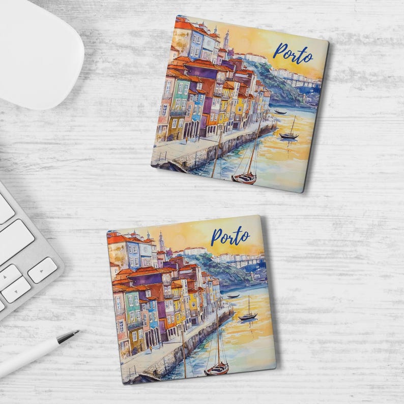 May include: Two square coasters with a watercolor painting of Porto, Portugal. The image features colorful buildings along a river, boats, and a bridge. The word "Porto" is written in blue script on each coaster.