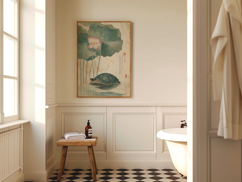May include: A bathroom scene featuring a framed artwork of a turtle in water with a lotus flower. A small wooden stool holds a rolled white towel and a brown bottle. The room has white paneling, a black and white checkered floor, and a white bathtub.