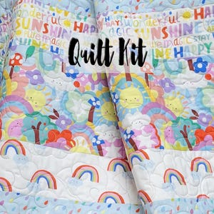 May include: A quilt kit featuring a colorful fabric with a repeating pattern of rainbows, clouds, suns, and mushrooms. The fabric has the words "Happy Days", "Sunshine", "Pure Magic", and "Quilt Kit" printed on it.