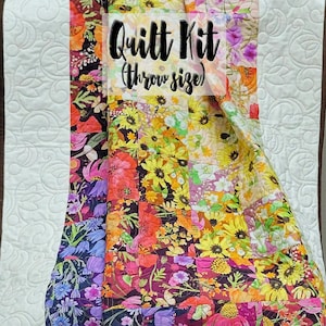 Puede incluir: Un colorido kit de edredón de tamaño individual, con un diseño de patchwork con vibrantes estampados florales en tonos rojos, amarillos, morados y azules. El edredón tiene un borde blanco acolchado con un patrón de remolino. El texto "Quilt Kit (Throw size)" es visible.
