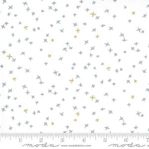 Puede incluir: Tela blanca con un patrón disperso de pequeñas cruces grises y doradas. La tela se mide en pulgadas con una regla en la parte inferior de la imagen. La regla tiene la palabra "moda" impresa en ella.