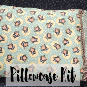 May include: A pillowcase kit featuring a teal fabric with a repeating pattern of black cats in yellow circles. The pillowcase has a brown and white patterned border. The text "Pillowcase Kit" is printed in black on a white background.