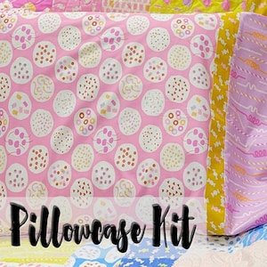 May include: A pink pillowcase kit with a pattern of white circles with colourful dots inside. The pillowcase has a yellow and pink striped border. The text "Pillowcase Kit" is written in black on a white background.