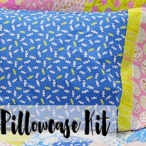 Puede incluir: Un kit de funda de almohada con una tela azul con un patrón de caramelos blancos y amarillos. El texto "Pillowcase Kit" está impreso en negro sobre un fondo blanco.