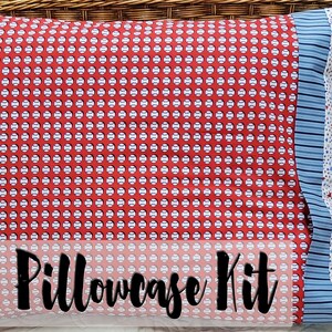 May include: A pillowcase kit featuring three fabric designs. The main fabric is red with a white baseball pattern. The other fabrics are blue striped and white with blue and red stars. The text "Pillowcase Kit" is on the front.