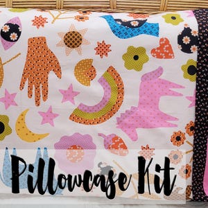 May include: A pillowcase kit with a playful design. The white fabric is decorated with colourful hand-drawn illustrations of hands, stars, flowers, and a unicorn. The pillowcase has a pink border and the words "Pillowcase Kit".