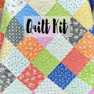 May include: A quilt kit featuring a variety of colorful floral patterned fabrics. The quilt is made up of squares arranged in a diamond pattern. The text "Quilt Kit" is written in black on a white background.
