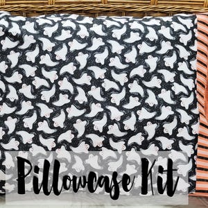 May include: A Halloween-themed pillowcase kit featuring a black and white ghost pattern. The kit includes fabric with a ghost print, orange fabric with black spiderwebs, and striped fabric. The words "Pillowcase Kit" are printed on the image.