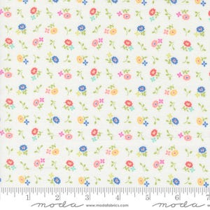 May include: Cream-colored fabric with a repeating pattern of small, colorful flowers. The flowers are in shades of red, blue, yellow, and pink, with green leaves. The fabric has a ruler printed along the bottom edge.