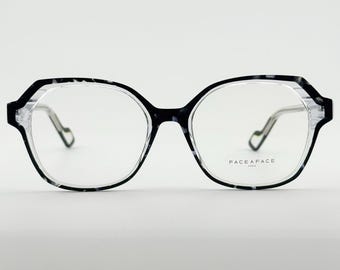 May include: Black and white patterned eyeglasses with a geometric frame. The glasses have clear lenses and thin silver arms. The brand name "FACE A FACE PARIS" is printed on the right lens.