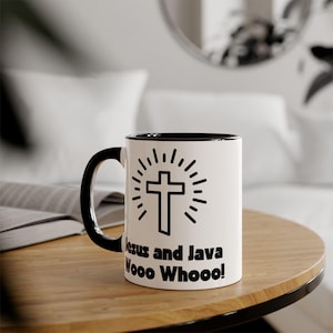 Peut inclure: Une tasse à café en céramique blanche avec un bord et une poignée noirs. La tasse présente un motif noir et blanc d'une croix avec un rayonnement solaire. Le texte "Jesus and Java Woo Hoo!" est imprimé sous le motif.