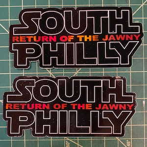 May include: Two black and white stickers with the text "SOUTH RETURN OF THE JAWNY PHILLY" in a bold, outlined font. The text is in a gradient of red, orange, and yellow.