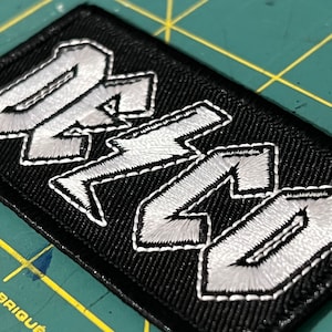 May include: Black embroidered patch with white lettering that reads "DR. MARTENS".