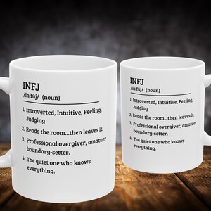 May include: Two white ceramic mugs with the text "INFJ" and a definition printed in black. The mugs are on a wooden surface. The text includes the definition of INFJ, a personality type.