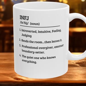 May include: White ceramic mug with the text "INFJ" and a definition. The definition includes phrases like "Introverted, Intuitive, Feeling, Judging" and "Reads the room...then leaves it."