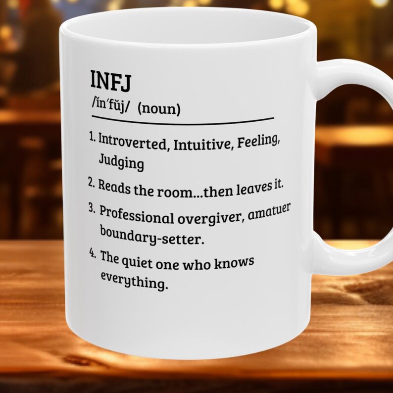May include: White ceramic mug with the text "INFJ" and a definition. The definition includes phrases like "Introverted, Intuitive, Feeling, Judging" and "Reads the room...then leaves it."