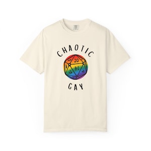 May include: Off-white t-shirt featuring the text "CHAOTIC GAY" above and below a rainbow D20 die graphic. The t-shirt is a short-sleeved crew neck style.