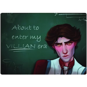 May include: A young person with brown hair and a white shirt stands in front of a green chalkboard. The chalkboard has white chalk writing that says "About to enter my VILLIAN era".
