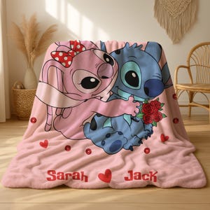 A pink blanket with a cartoon image of two cartoon characters, a pink bunny and a blue dog, sitting together and holding a bouquet of flowers. The blanket has the names 'Sarah' and 'Jack' printed on it.