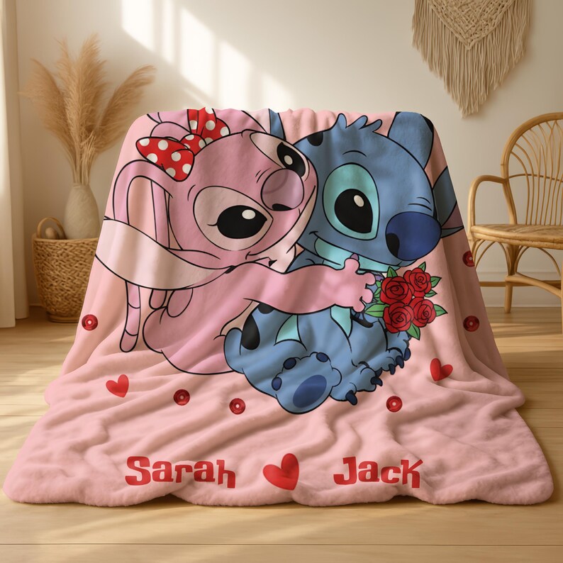 A pink blanket with a cartoon image of two cartoon characters, a pink bunny and a blue dog, sitting together and holding a bouquet of flowers. The blanket has the names 'Sarah' and 'Jack' printed on it.