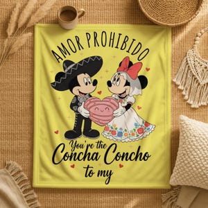 a yellow blanket with a cartoon illustration of Mickey Mouse and Minnie Mouse, along with text that says "Amor Prohibido" and "You're the Concha Concho to my".