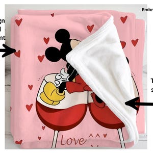 a pink blanket with a cartoon character, specifically Mickey Mouse, sitting in a wine glass. The blanket is embroidered with the character and the word "Love".