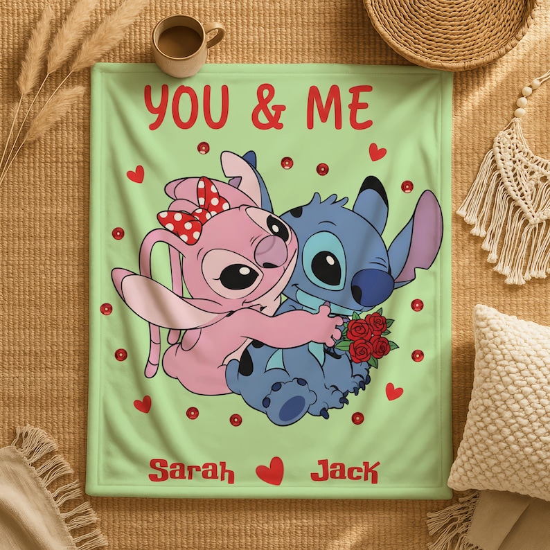 a blanket with a cartoon illustration of two characters, a pink bunny and a blue dog, hugging each other. The blanket has a message that reads "You & Me" and the names "Sarah" and "Jack" written below the illustration.