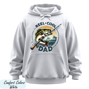 A white hoodie with a graphic design featuring a fish and the text "REEL. COOL. DAD" printed on it.
