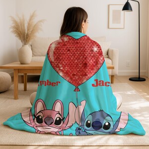 A woman is sitting on the floor, wrapped in a blanket featuring the characters from the Disney movie Lilo & Stitch.