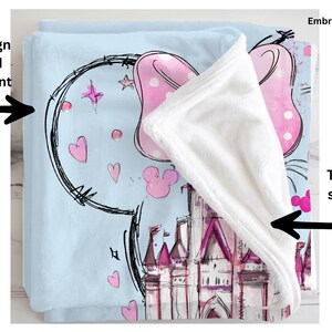 a blue blanket with a cartoon castle design, including Mickey Mouse and other whimsical elements. The blanket is printed on the front, and the back is solid white.