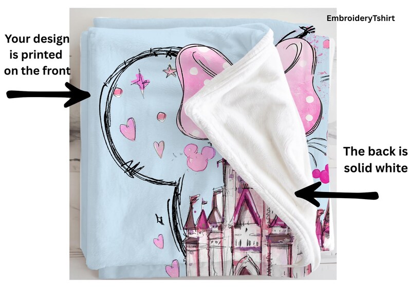 a blue blanket with a cartoon castle design, including Mickey Mouse and other whimsical elements. The blanket is printed on the front, and the back is solid white.