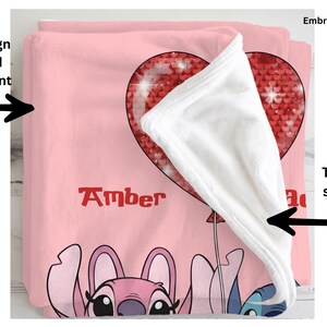a pink blanket with a cartoon character design, including a heart-shaped balloon and a character with a pink hat.