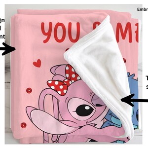 a pink blanket with a cartoon character design, including a bow and hearts. The blanket is folded over itself, revealing the back, which is solid white. The blanket is printed on the front, and the back is solid white.
