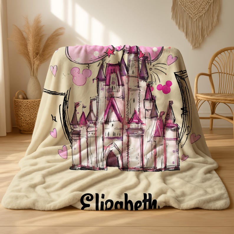 A beige blanket with a castle design and hearts printed on it, placed on a wooden floor.