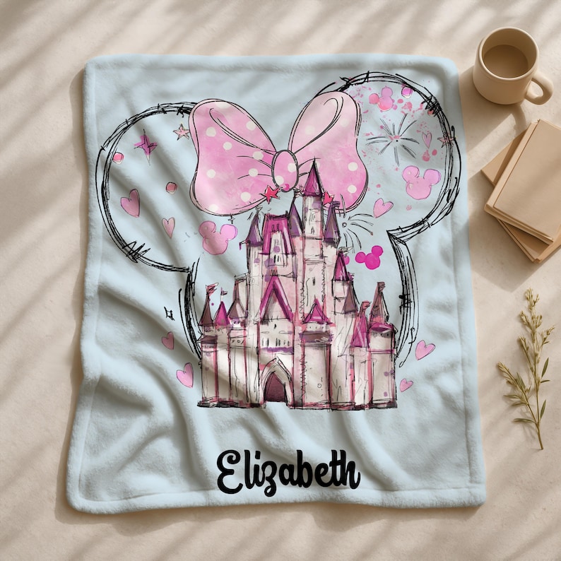 A personalized blanket featuring a cartoon illustration of a castle with a pink bow and hearts, along with the name "Eliza" written on it.