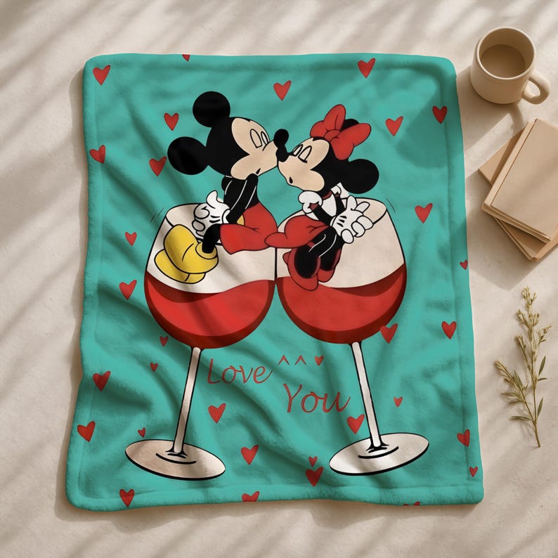 A blanket with a cartoon image of Mickey Mouse and Minnie Mouse sitting together in wine glasses, surrounded by red hearts, with the text "Love You" written on it.