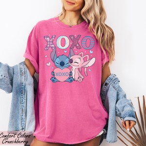 A woman wearing a pink t-shirt with a cartoon character and the text "XOXO" is posing in front of a plant.