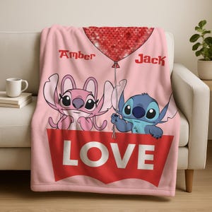A pink blanket with a cartoon character design and the word "LOVE" written on it.