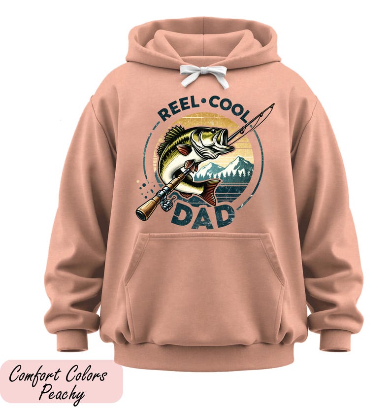 A peach-colored hoodie with a graphic design featuring a fish and the text "REEL-COOL DAD" printed on it.