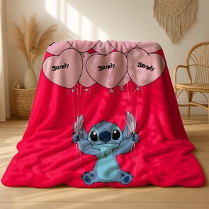 a red blanket with a cartoon character, specifically a blue character resembling Stitch from the movie Lilo and Stitch, holding balloons.
