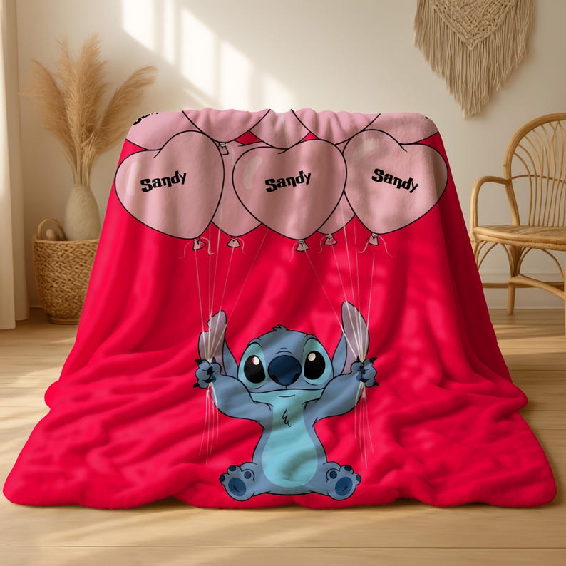 a red blanket with a cartoon character, specifically a blue character resembling Stitch from the movie Lilo and Stitch, holding balloons.