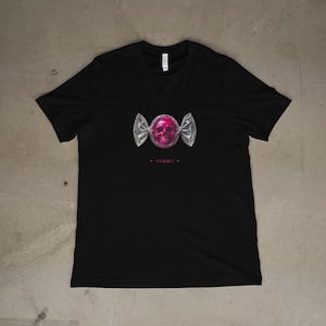 May include: Black t-shirt featuring a pink skull candy graphic. The candy is wrapped in silver foil with the word "YUMMY" printed below the graphic. The shirt is made of a soft material.
