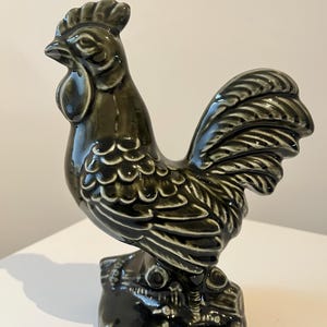 Puede incluir: Figura de gallo de cerámica con un esmalte verde oscuro brillante. El gallo está sobre una base texturizada, con plumas detalladas y una cresta prominente. La figura es un artículo decorativo, adecuado para la decoración del hogar.